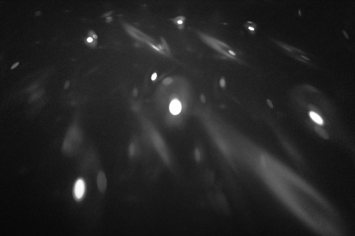 Animierte Fotoaufnahmen in Schwarz-Weiß von sich langsam bewegenden Lichtern auf dunklem Boden.